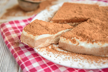 Homemade layered cottage cheese souffle dessert with cocoa on white wooden table