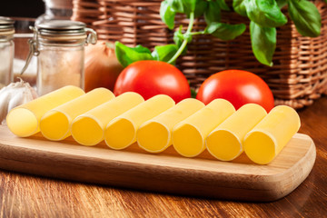 Uncooked cannelloni pasta on cutting board and ingredients