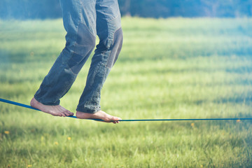 Slackline. Close up on feet walking on tightrope outdoor in a city park