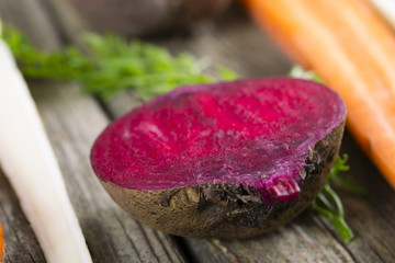 Obraz premium sliced raw vegetables: carrot, turnip, beetroot and parsley on old wooden table background