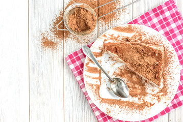Homemade layered cottage cheese souffle dessert with cocoa on white wooden table