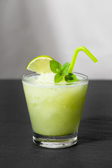 Cocktail juice with lime, mint and ice. Bar drink accessories on black table background.