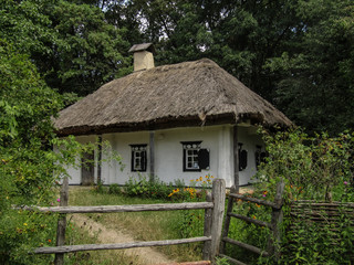 Fototapeta na wymiar An old Ukrainian white mud house under a thatched roof, a whitewashed 