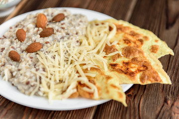 Oatmeal with omelette and cheese on dark wooden table. Healthy breakfast.