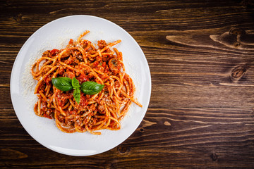 Pasta with meat and tomato sauce on wooden table