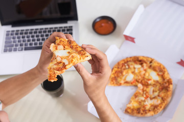 Business people working at office desk and having a lunch break with a tasty pizza,