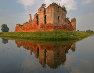 Malowniczy pejzaż z ruinami średniowiecznego zamku na porośniętej trawą wyspie, piękne lustrzane odbicie budowli w otaczającej go wodzie