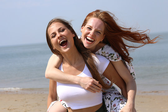 Zwei h&uuml;bsche junge Frauen haben Spa&szlig; an einem Strand Meer im Hintergrund
