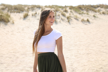 Fototapeta premium Hübsche junge Frau an einem Strand lächelt und schaut in eine Richtung
