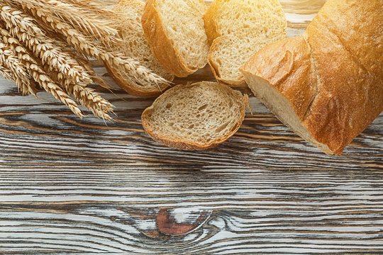 Crusty sliced bread rye ears on wooden surface