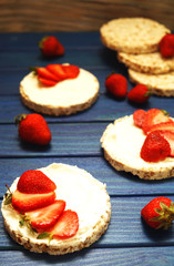 healthy Breakfast and a snack of rice bread with red strawberries, with cheese on a blue wooden background