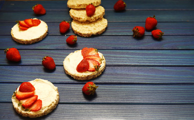 healthy Breakfast and a snack of rice bread with red strawberries, with cheese on a blue wooden background