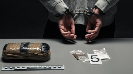 hands of a male drug dealer are handcuffed. The fight against drugs and crime