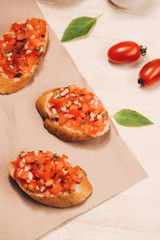 Italian bruschetta with roasted tomatoes, mozzarella cheese and herbs on a paper