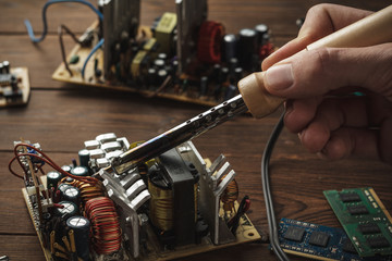 Master soldering radio components, repairing a computer with a hand in the frame