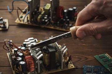 Master soldering radio components, repairing a computer with a hand in the frame