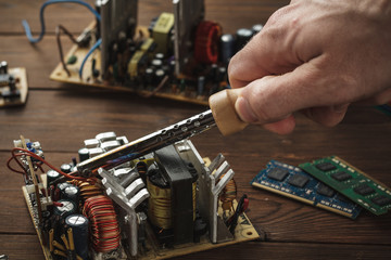 Master soldering radio components, repairing a computer with a hand in the frame