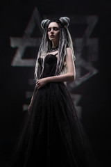 Naklejka premium Side view of woman with dreads and festive black gothic dress posing on dark background