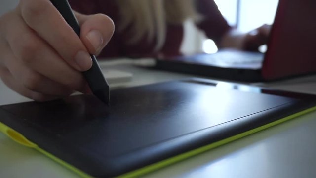 Close up female hand using stylus graphic tablet board at her office