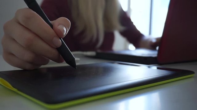 Close up female hand using stylus graphic tablet board at her office