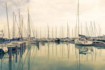 Fototapeta na wymiar Warm peaceful landscape with sailboats moored in the dock .Their reflection in water.