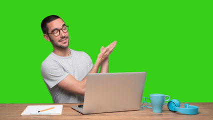 Confident young man sitting at his desk and showing something with his hands - Green background