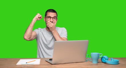 Angry young man sitting at his desk - Green background