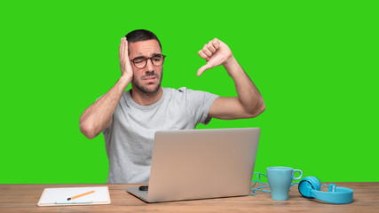 Loser young man sitting at his desk - Green background