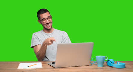 Funny young man sitting at his desk - Green background