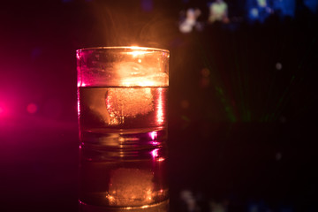 selective focus pure whisky with ice cube inside whisky glass on dark foggy background alcohol drink concept.