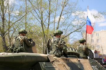 The soldiers are standing in the open hatches of the tank. The Russian military on military...