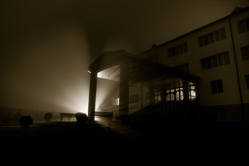 Old house with a Ghost in the forest at night or Abandoned Haunted Horror House in fog. Old mystic building in dead tree forest. Creepy house in the middle of a dark forest.