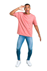 Fototapeta premium Standing young african american man with surprise and shocked facial expression. Gaping because can not believe what is happening on isolated white background