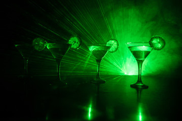 Several glasses of famous cocktail Martini, shot at a bar with dark toned foggy background and disco lights. Club drink concept.