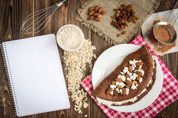 Homemade chocolate oat pancake with cottage cheese on white plate on dark wooden table