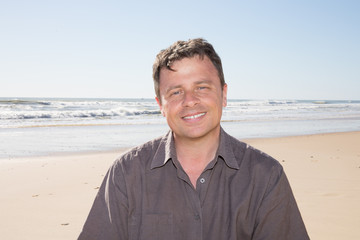 handsome smiling man face with sand sea beach background