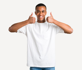 Young african american man giving a thumbs up gesture and smiling because has had success on isolated background