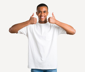Fototapeta premium Young african american man giving a thumbs up gesture and smiling because has had success on isolated background