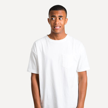 Young african american man is a little bit nervous and scared pressing the teeth on isolated background