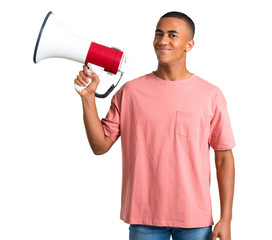 Young african american man holding a megaphone on isolated white background
