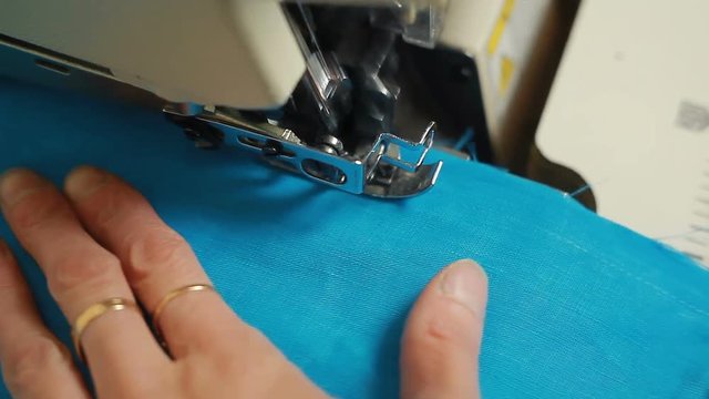 Close-up of woman's hands sewing an overlock at sewing machine.