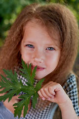 The baby is 4 years old, with blue eyes and small curls. Children's enjoyment of life and adventures. Warm Golden sunset light.Looking away, dreamy, face leaf