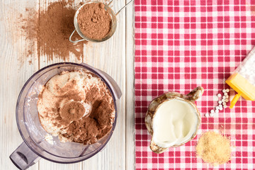 Ingredients for homemade cottage cheese souffle dessert with cocoa on white wooden table. Recipe of healthy dessert.