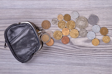 Leather purse and coins. Top view. Wooden desk background.