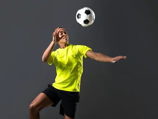 Foto op Plexiglas Soccer player man with dark skinned playing hitting head on dark background © luismolinero