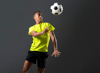 Soccer player man with dark skinned playing hitting head on dark background
