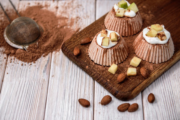 Homemade chocolate cottage cheese souffle with cocoa, apple and almond on white wooden background.