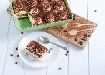 Tiramisu tray with portion on a plate on white background. Flat lay.