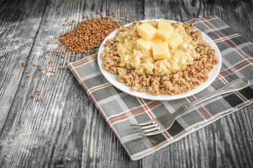 Chicken gravy with buckwheat porridge and cheese on white plate on grey wooden background. Healthy dinner.