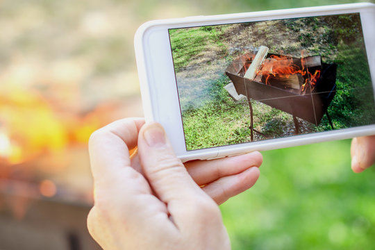 Human hands is taking pictures of the fire on smartphone. Outdoors.
